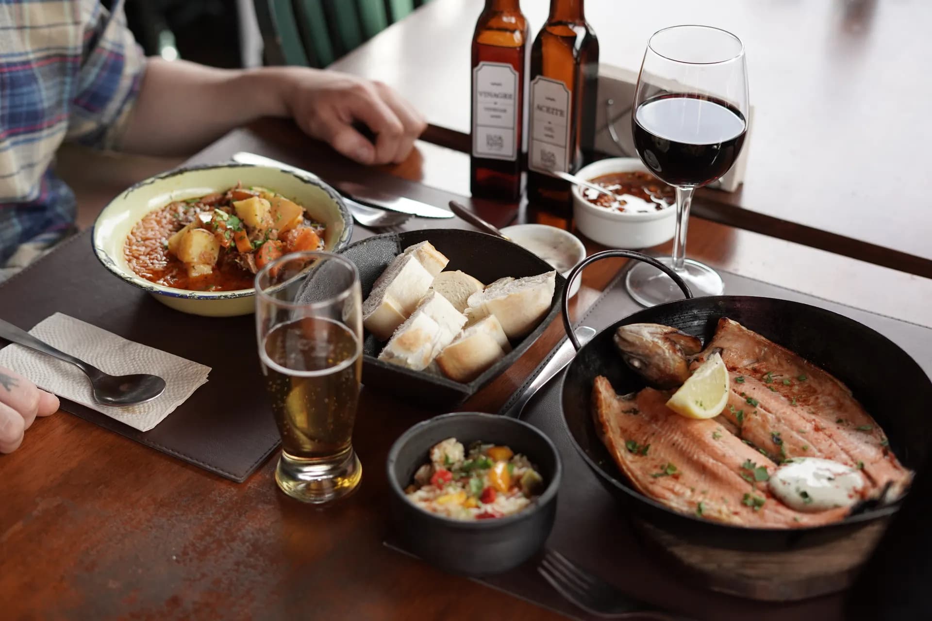 Mesa servida com truta, pão caseiro, vinho e entradas