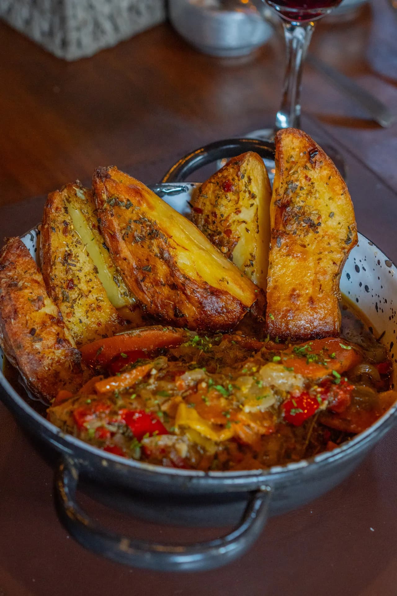 Batatas rústicas douradas sobre refogado de legumes